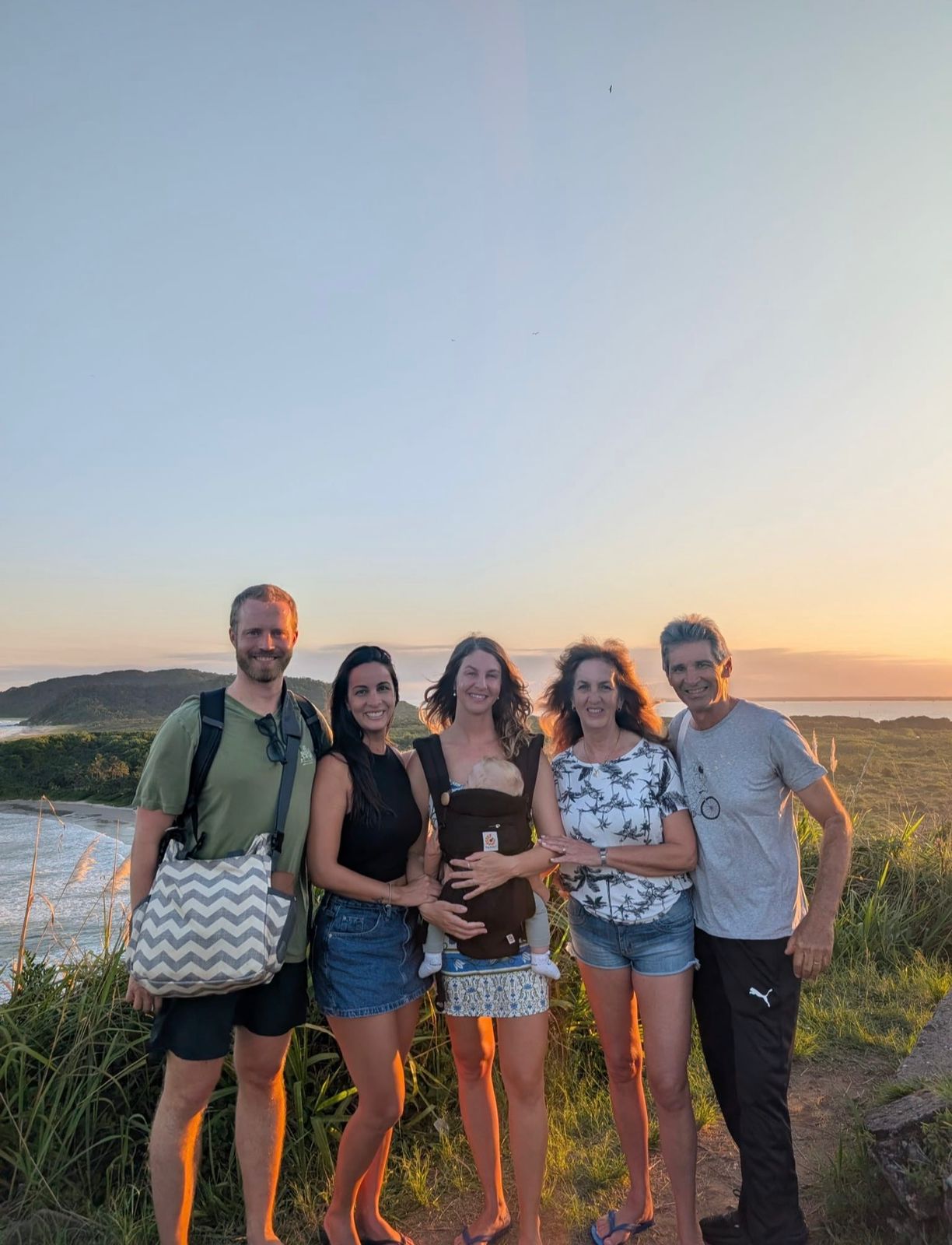 Leticia with a family at sunset, holding a baby in a carrier